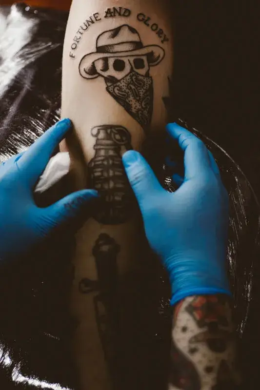 Person with gloves holding a tattooed arm.